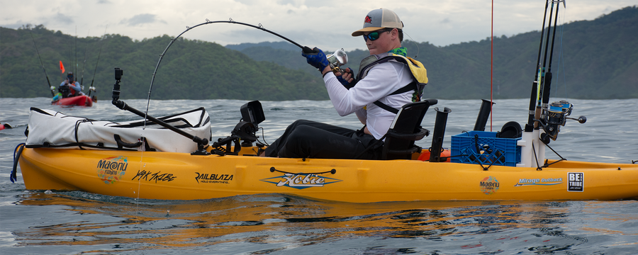 man hooking a fish on a yellow hobie kayak